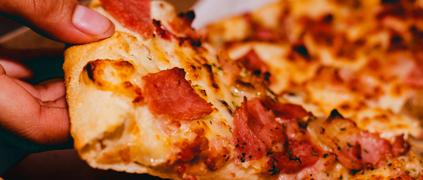 Person lifting slice of pizza.