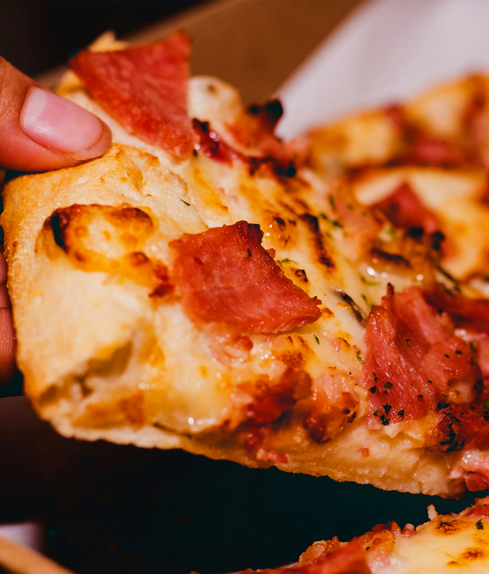 Person lifting slice of pizza.